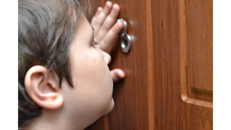 A teenage boy looking through peephole.