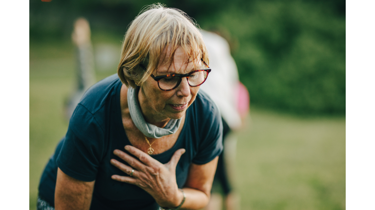 Tired senior woman with eyeglasses sweating after exercise at park