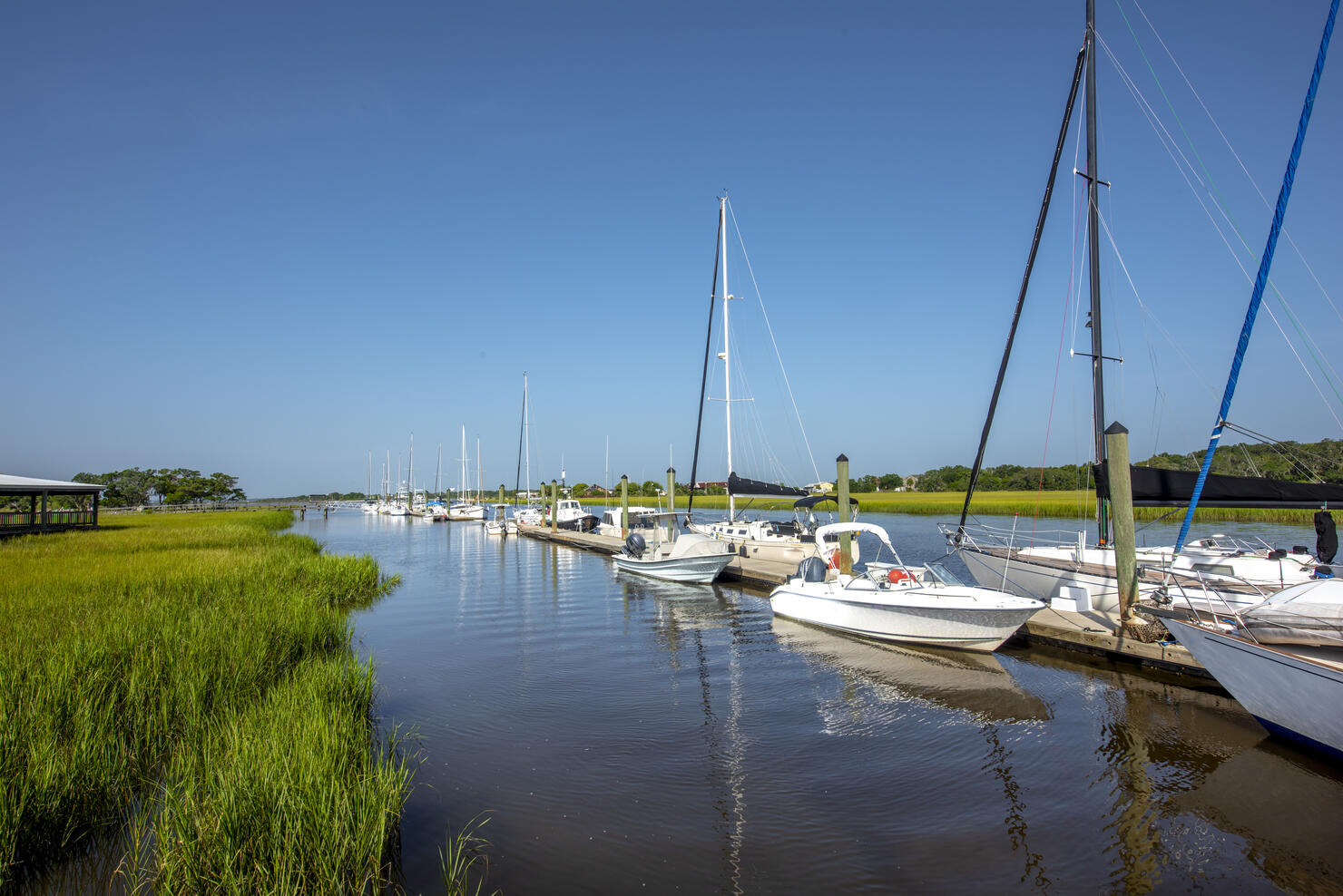 Sail Boats Moored At Harbor Against Blue Sky