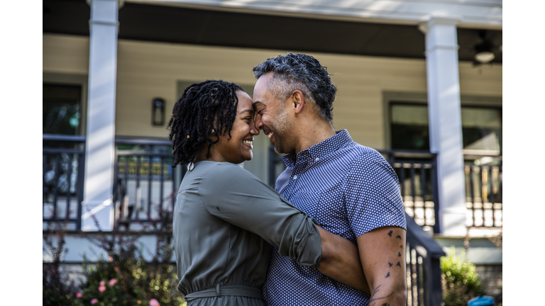 Husband and wife embracing in front of new home