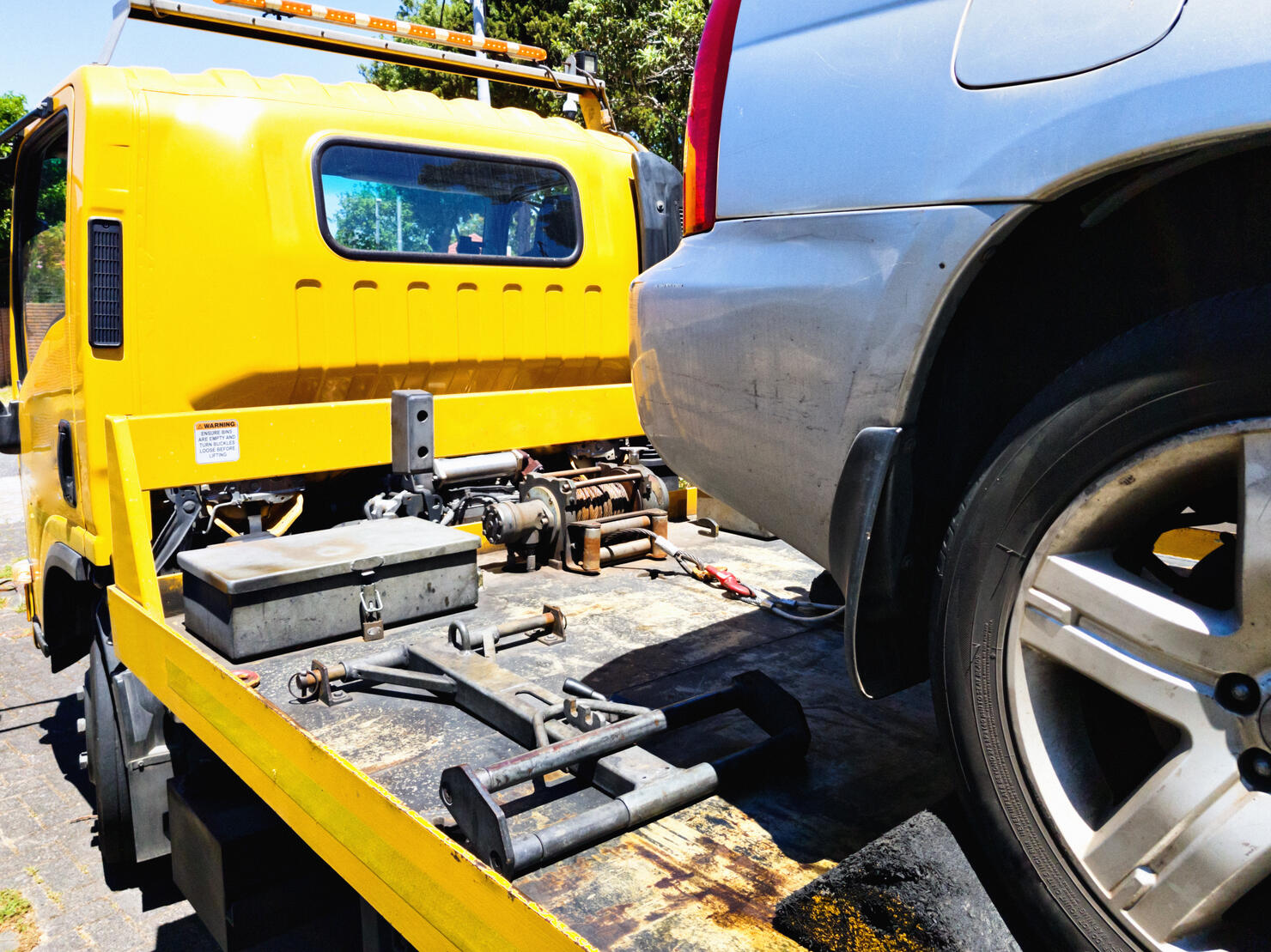 Car being secured to a flatbed tow truck after breakdown