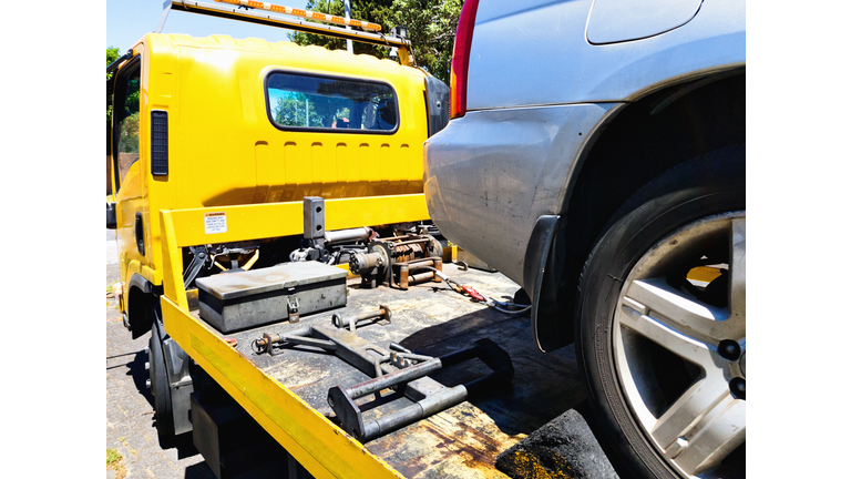 Car being secured to a flatbed tow truck after breakdown