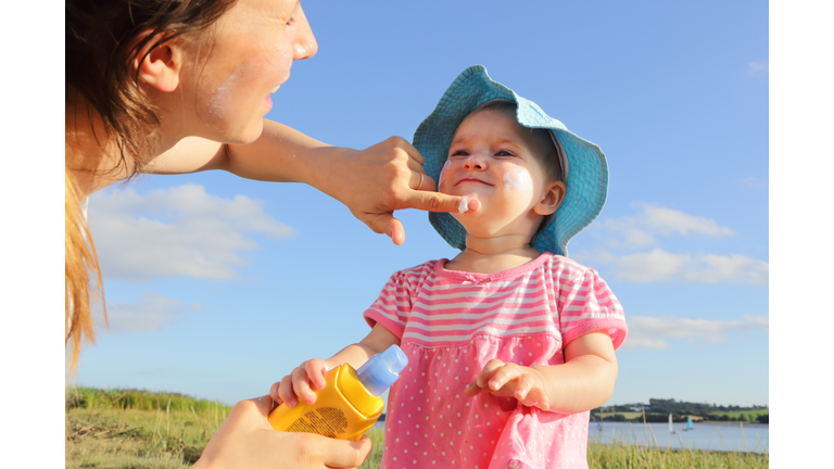 Mother putting sun cream on toddler girl