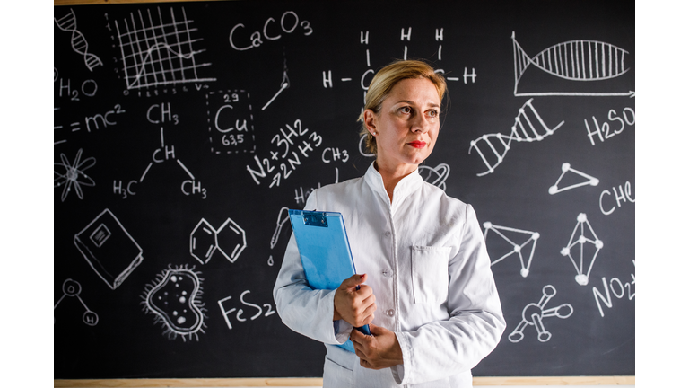 Science teacher in front of the blackboard