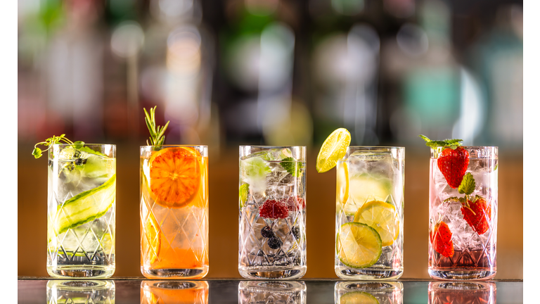 Five gin tonic cocktails in wine glasses on bar counter in pup or restaurant.