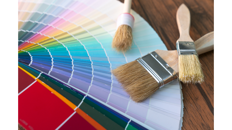 Painter and decorator work table with house project, color swatches, painting roller and paint brushes