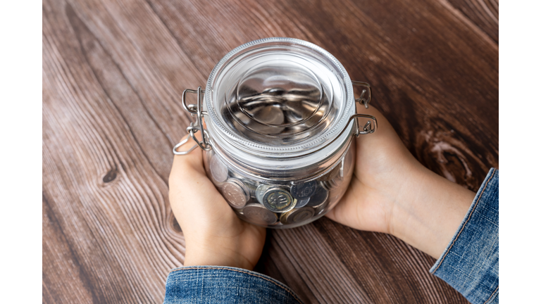 Hand Holding Coins Jar