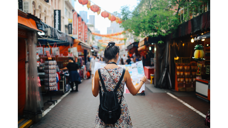 young solo traveler woman in Singapore street market checking the map