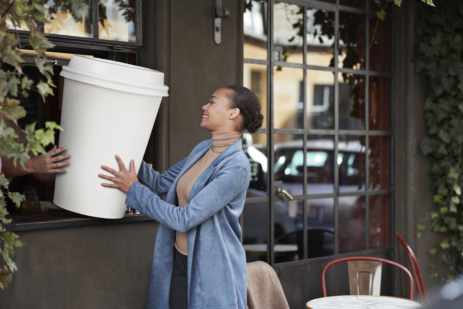 Woman holding large disposable coffee cup at take away counter of cafe