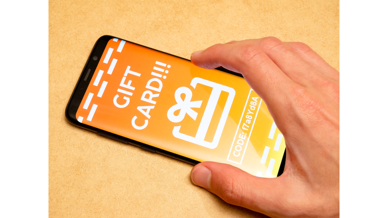 Man redeeming a generic gift card voucher on his smartphone, receiving a coupon code in app, mobile phone, hand closeup. Online advertising, internet marketing campaign simple concept, one person