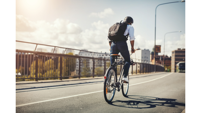 Rear view of businessman riding bicycle on bridge in city