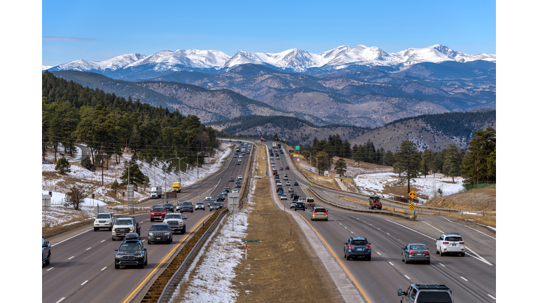 Highway and Snow Peaks - A sunny Winter day view of busy Interstate Highway I-70, with snow-capped high peaks of Continental Divide towering at west. Denver, Colorado, USA.