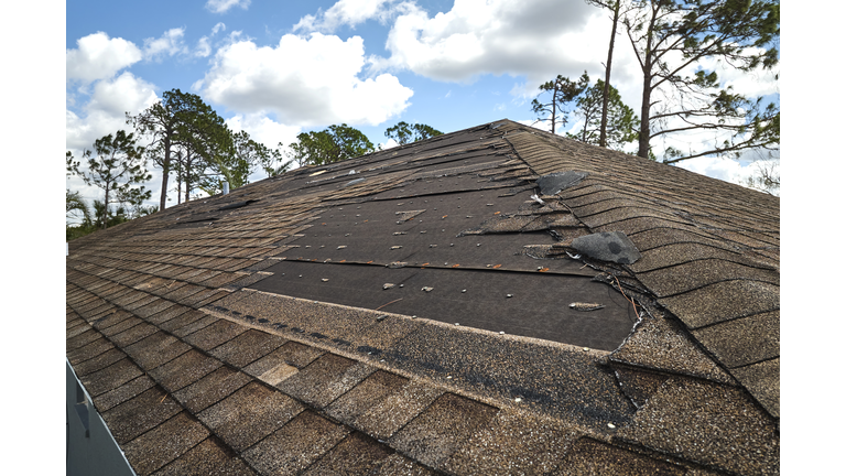 Wind damaged house roof with missing asphalt shingles after hurricane Ian in Florida. Repair of home rooftop concept