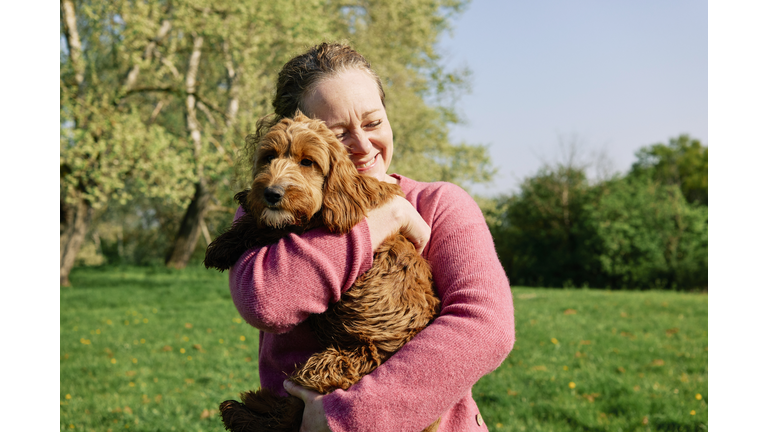 Woman cuddling her dog in a field