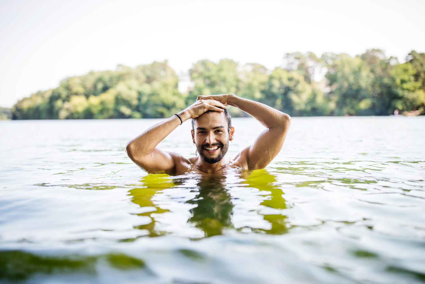 Handsome young man swimming in lake