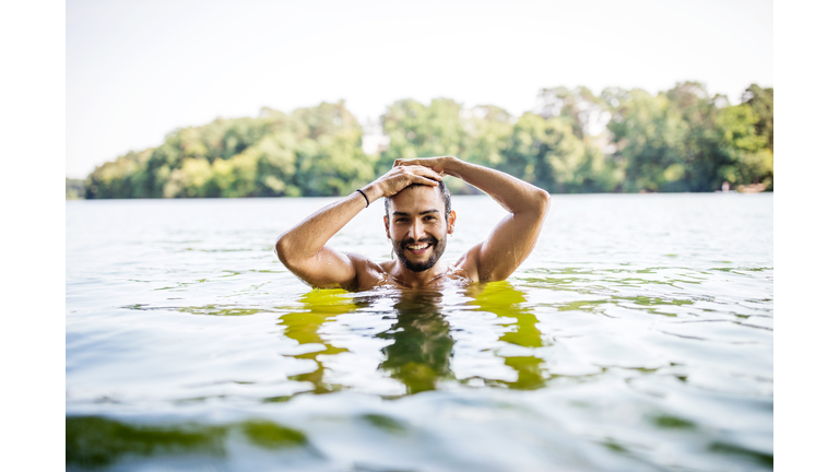 Handsome young man swimming in lake