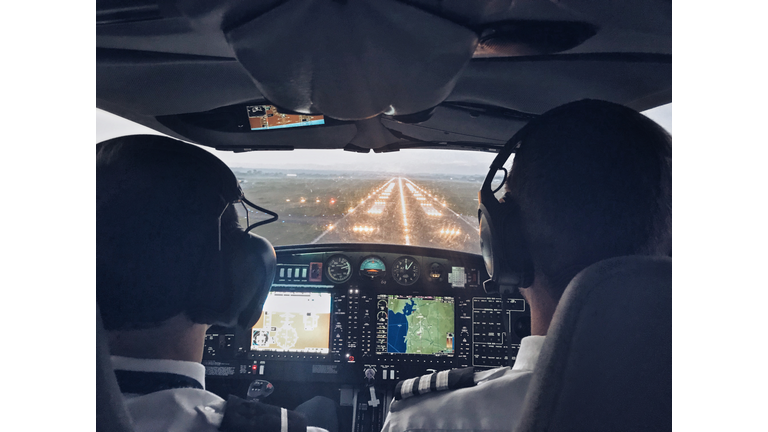 Pilot in cockpit of small private aircraft landing at night.