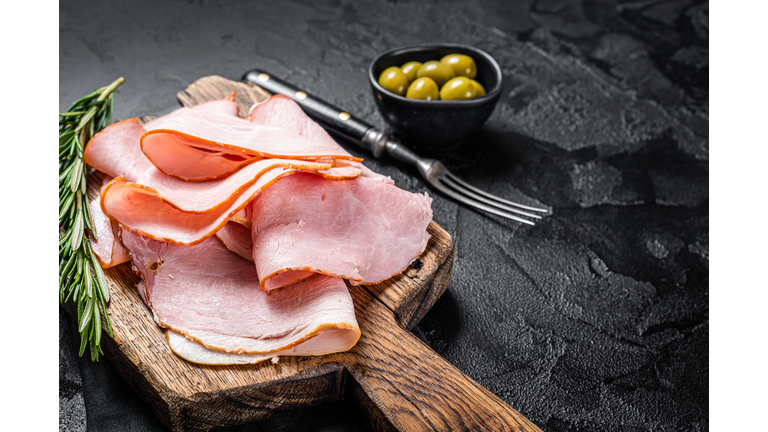 Pork ham slices on cutting board, Italian Prosciutto cotto. Black background. Top view. Copy space