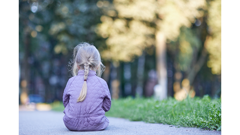 Little girl is sitting on the ground and crying