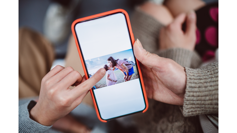Close-up of mom & daughter’s hands using smartphone together