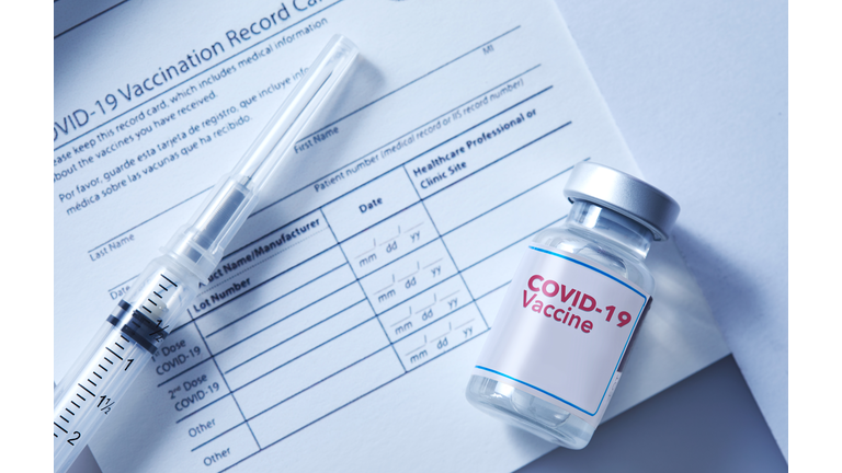 Covid-19 vaccination record card with a vial of a Covid-19 booster dose