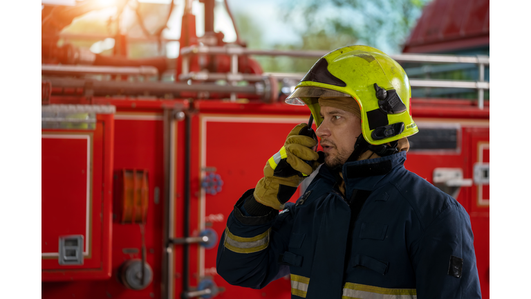 Fireman wearing protective uniform and talking on the radio.