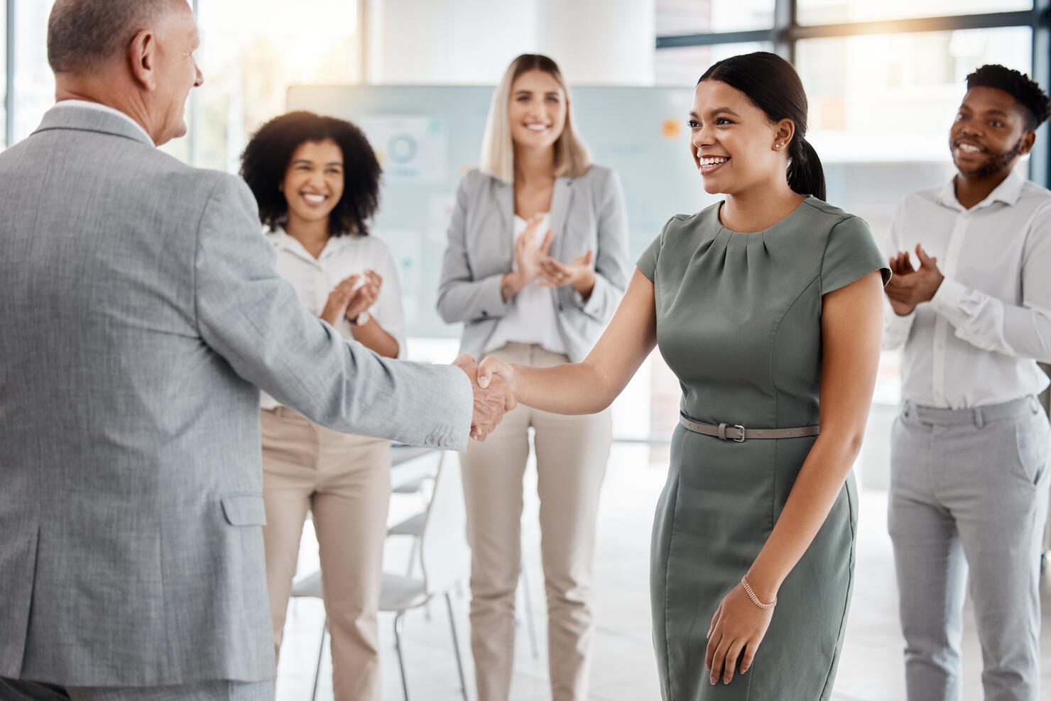 Happy handshake, by man and woman in office, for promotion in business, team gives applause. Meeting with diversity in people celebrate worker's progress to new role in corporate marketing job.