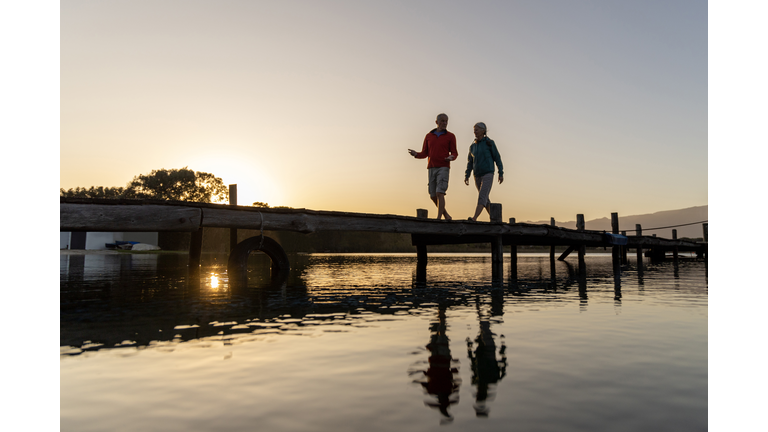 Senior couple walking on jetty at sunset