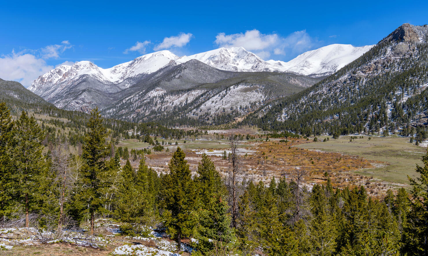 Spring at Rocky Mountain National Park - A panoramic view of Rocky Mountain National Park on a sunny morning after a Spring snowstorm, with snow-capped Mummy Range towering in background, Colorado, USA.