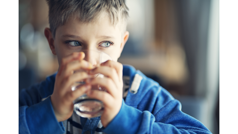 Portrait of a cute little boy drinking a glass of water