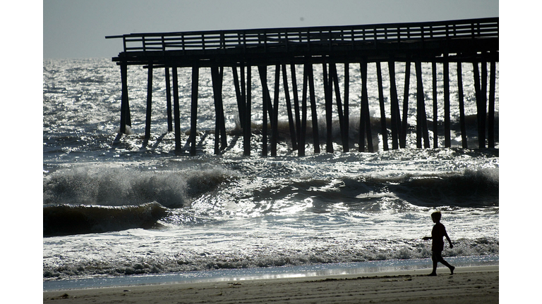 A young boy walks along the beach near a