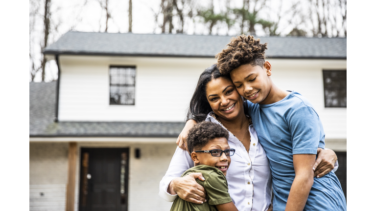 Portrait of mother and sons in front of residential home