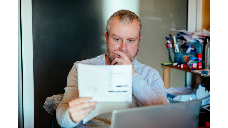 Worried man checking bills at home