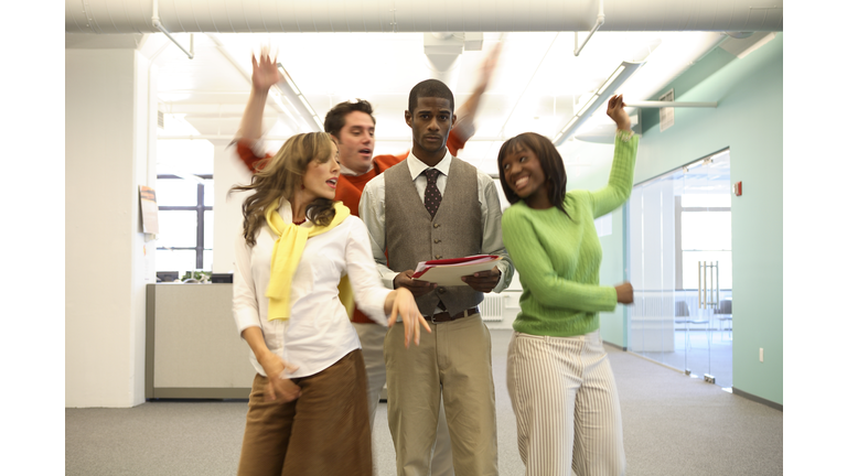 Workers dancing around serious colleague in office