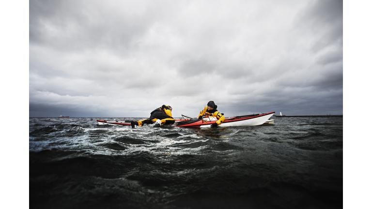 Freinds in kayak helping each other