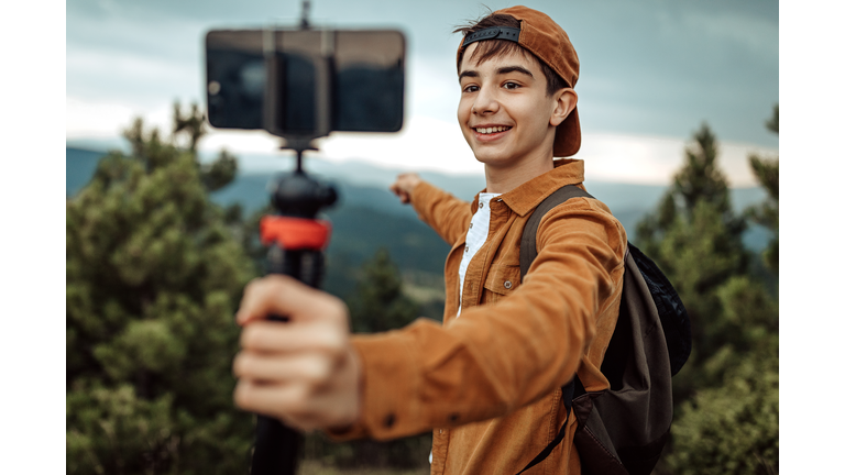 Boy hiking and vlogging using mobile phone