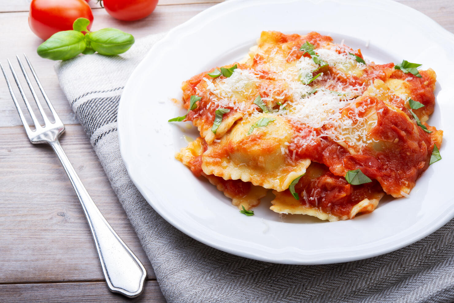 Homemade spinach and ricotta ravioli with tomato sauce and parmesan, close-up.