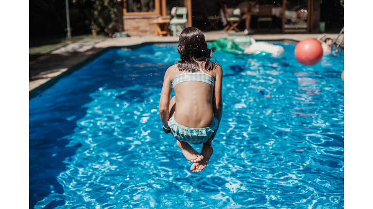 girl jumping into swimming pool