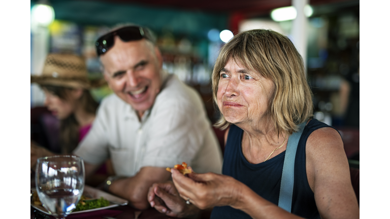 Senior woman tries a new dish in a restaurant.