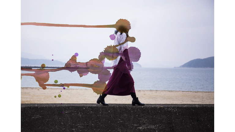 A woman walking along the beach which became a painting where the head turned red