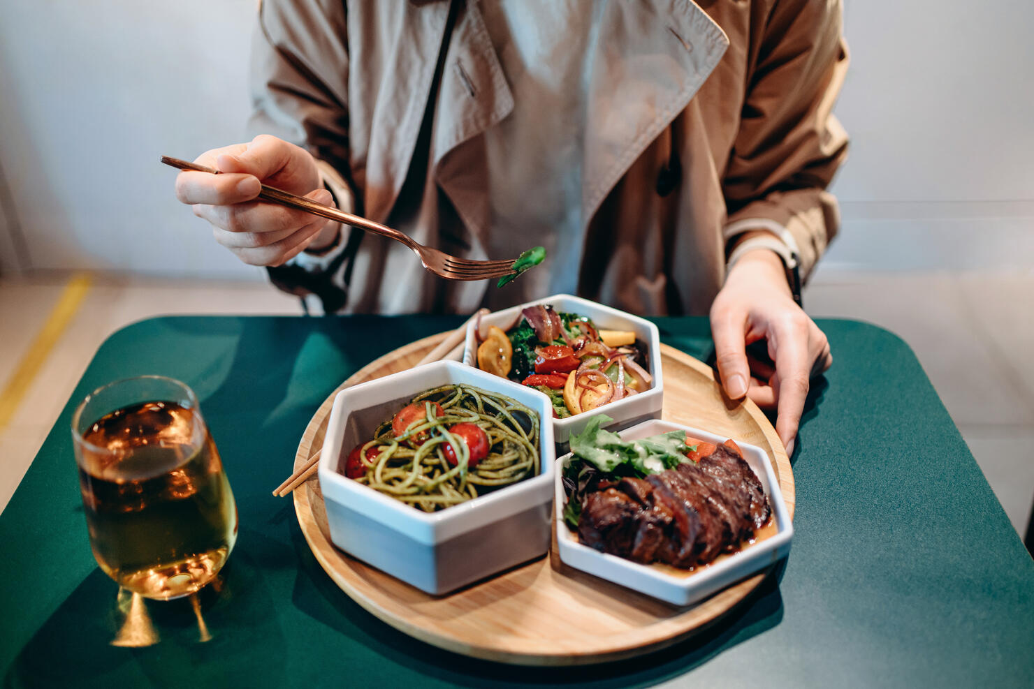 Close up of young Asian woman enjoying fusion food in a stylish restaurant. The meal set is freshly served on a  wooden tray with various nutritional ingredients to create a balanced and healthy diet. Farm-to-table, healthy eating concept