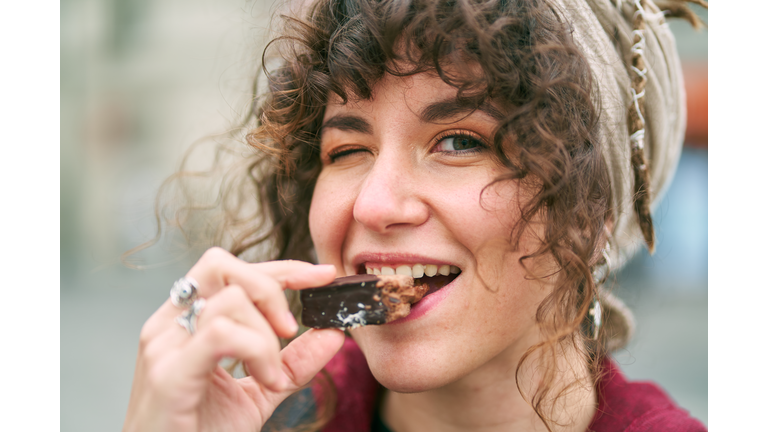 Cheerful woman eating candy on street