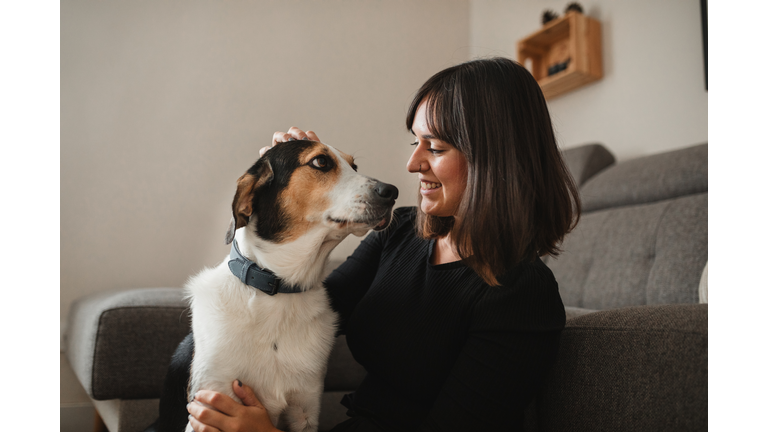 caucasian adult woman with her dog at home hugging