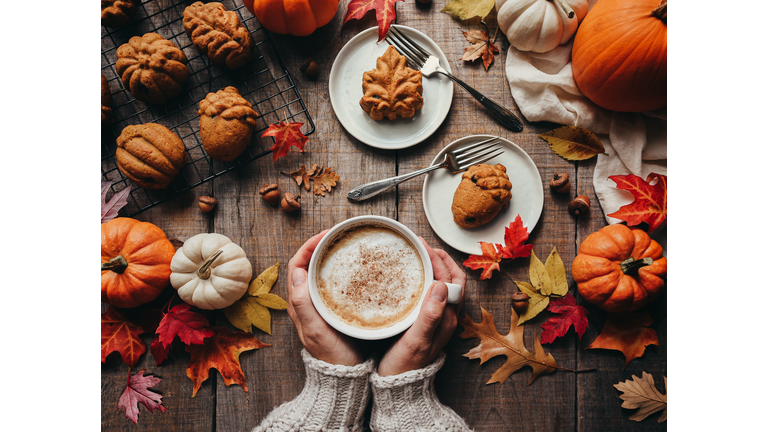 Top view of fall shaped pumpkin spice cakes and hands holding latte