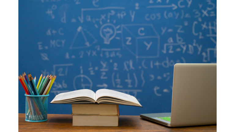 Back to school supplies. Books and blackboard on wooden background