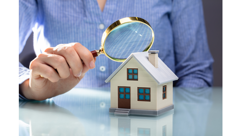 Businesswoman Holding Magnifying Glass Over House Model