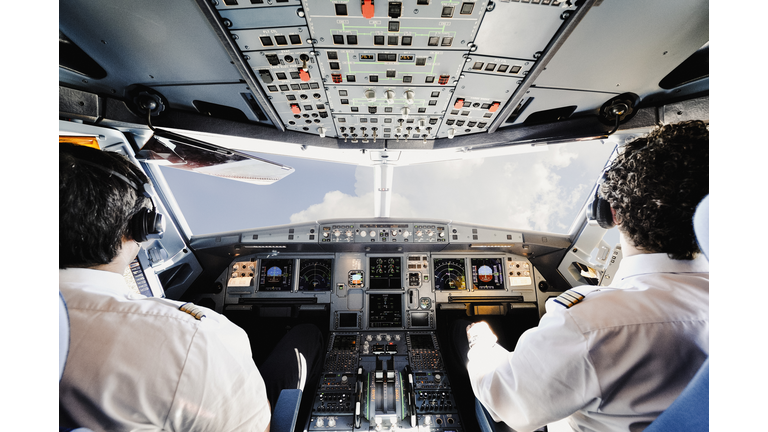 Two pilots in the cockpit of a modern passenger jet aircraft.