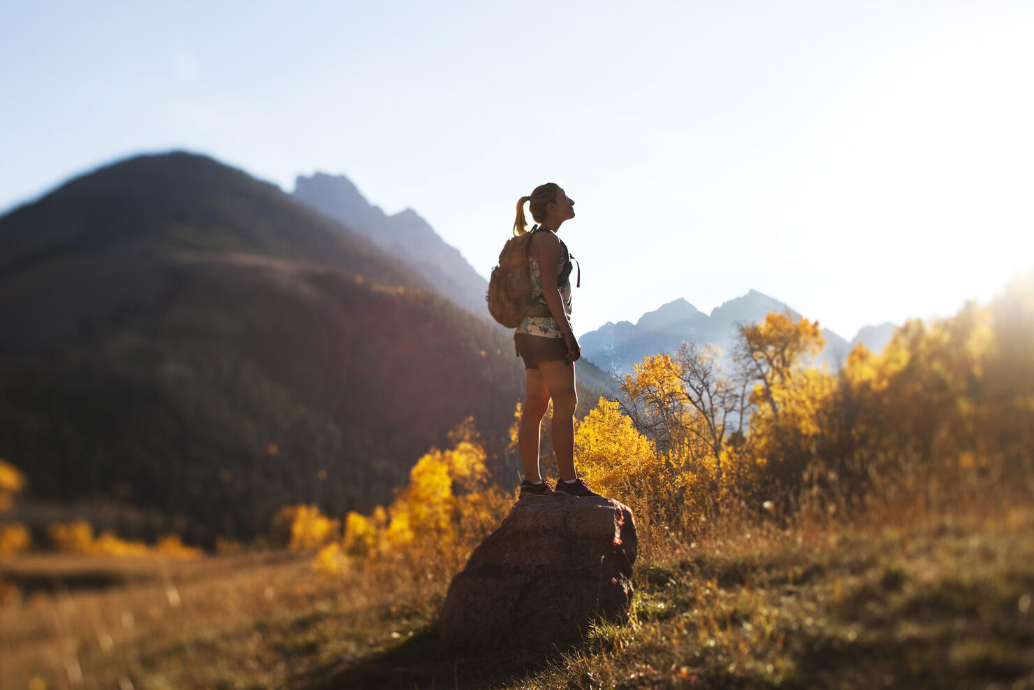 A young woman hiking stops and enjoys the beauty of the golden fall colors.