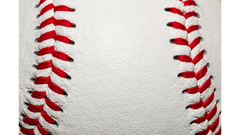 A macro of a baseball with red stitching and room for copy on the ball