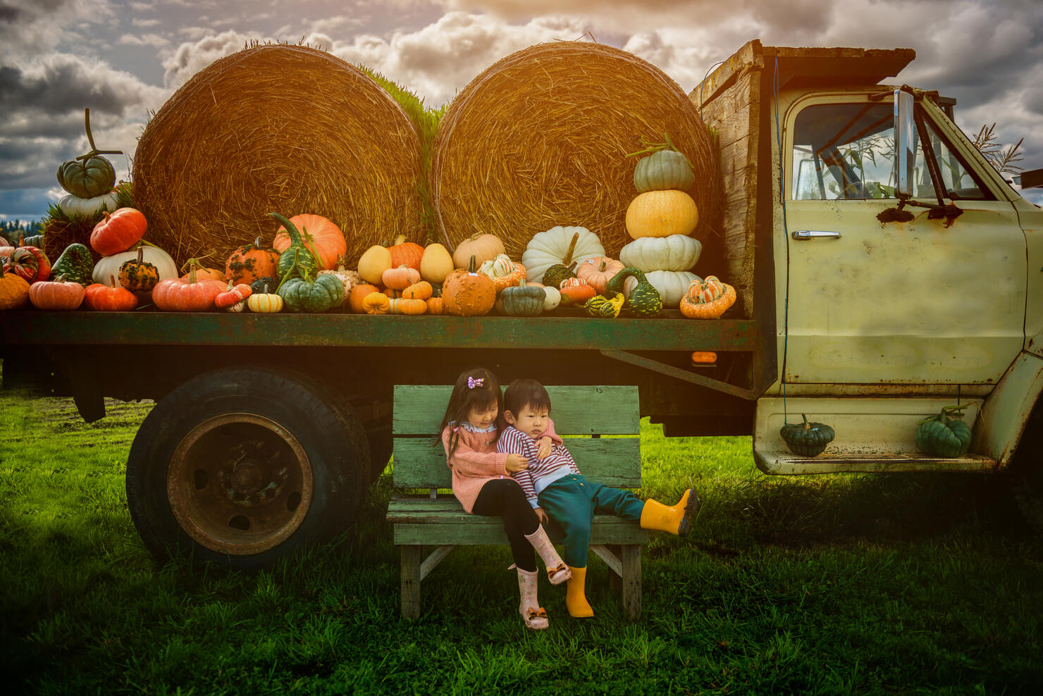 Siblings siting on the bench in front of tractor at pumpkin patch.